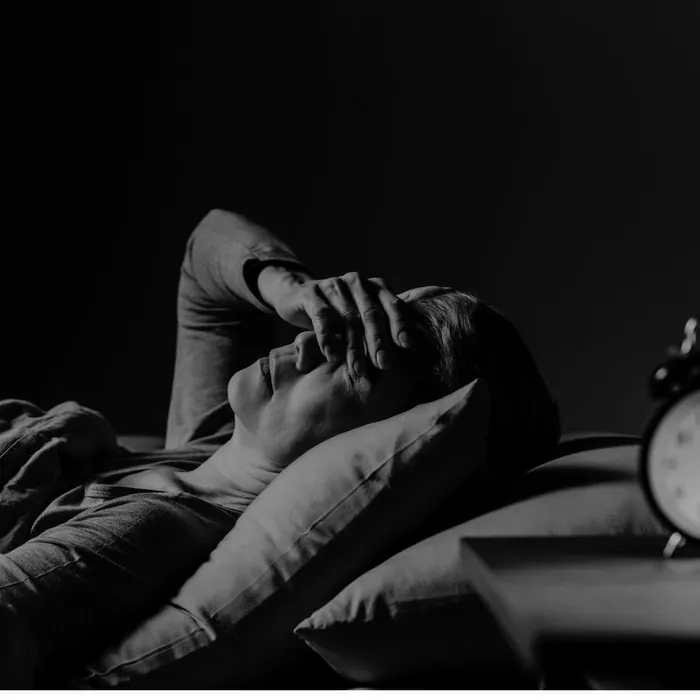 Une personne assise dans son lit la nuit, la tête dans les mains
