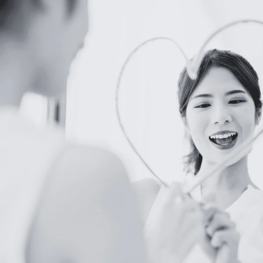 Une femme souriante qui se regarde dans un miroir